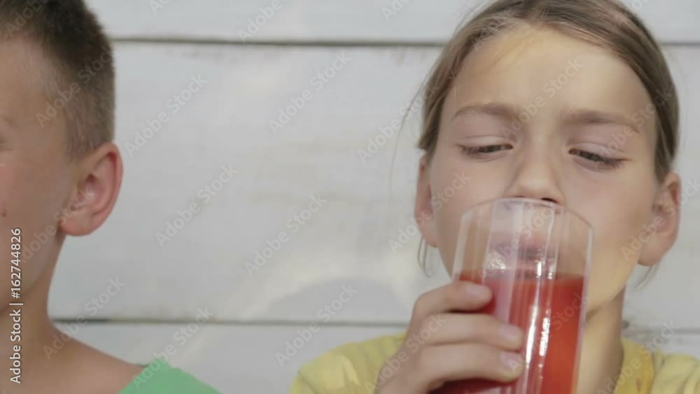 Boys drink orange and tomato juice. Children drink juice looking in a movie camera.
Boys drink orange and tomato juice. Children drink juice looking in a movie camera.