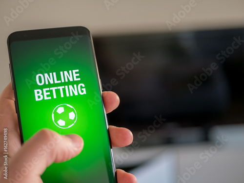 Billede på lærred Online sports betting app on smart phone. Man holdning device.