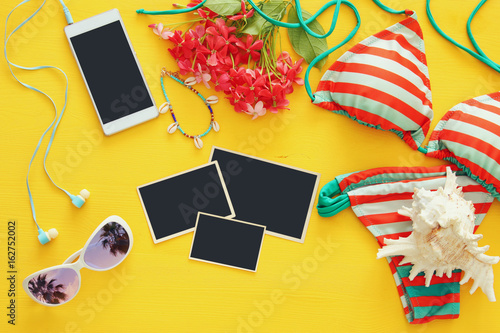 Top view of fashion female swimsuit bikini on yellow wooden background