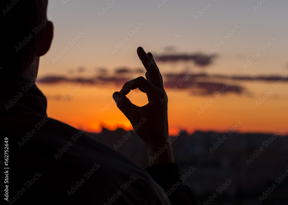 Fototapeta premium Everything is OK. A man at sunset. Figure of the fingers.