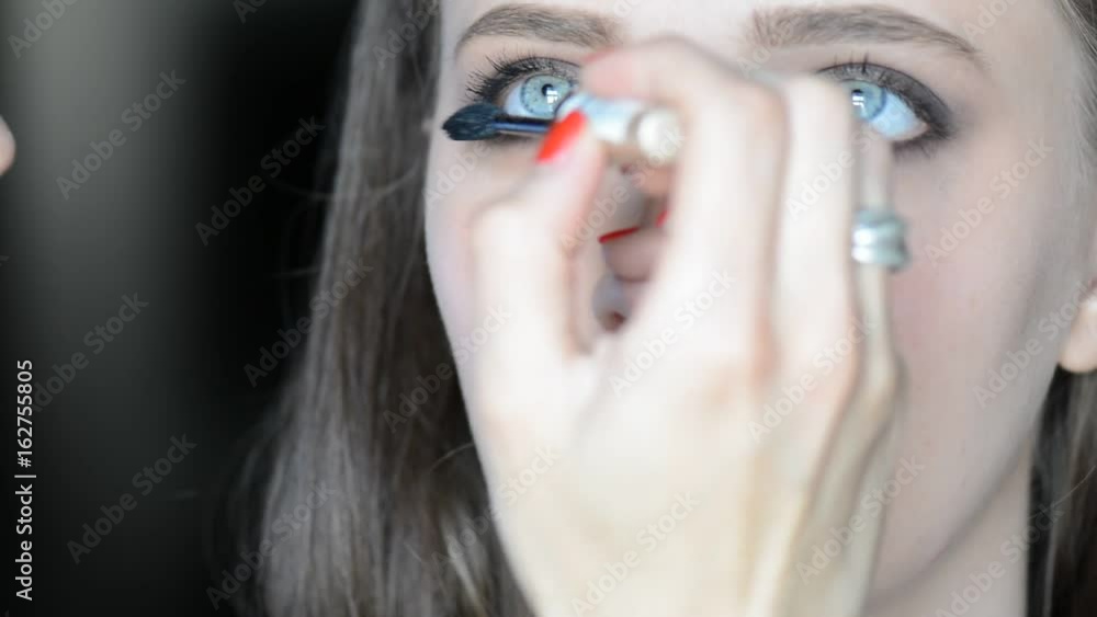 Make-up artist putting on make-up on model's eyes with cosmetic equipment. Eye mascara make-up. Make-up artist putting on make-up on model's eyes with cosmetic equipment. Eye mascara make-up.