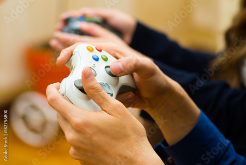 Close up hand holding a gamepad to play video games on the couch, concept about home entertainment, video games photo