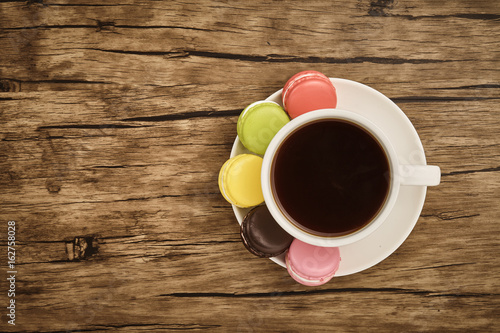 Colorful macaron and cup of coffee with wooden table
