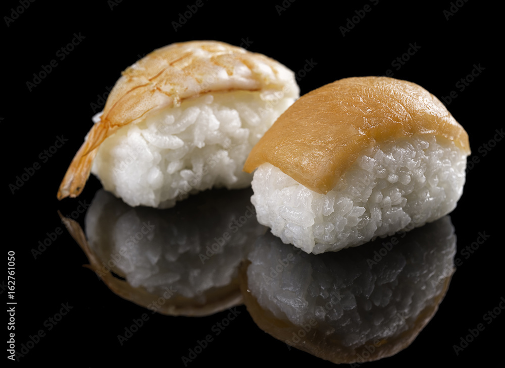Sushi with salmon and shrimps on a black background with reflection. Sushi with salmon and shrimps on a black background with reflection.