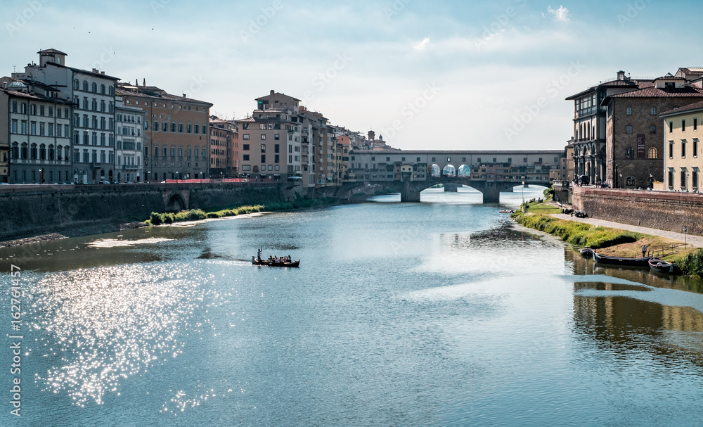 small tourist boat floating on the Arno river  near the Ponte Vecchio in Florence