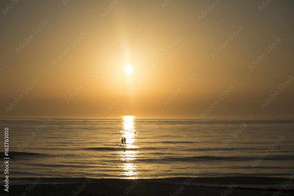 Ocean sunrise and paddle boarders