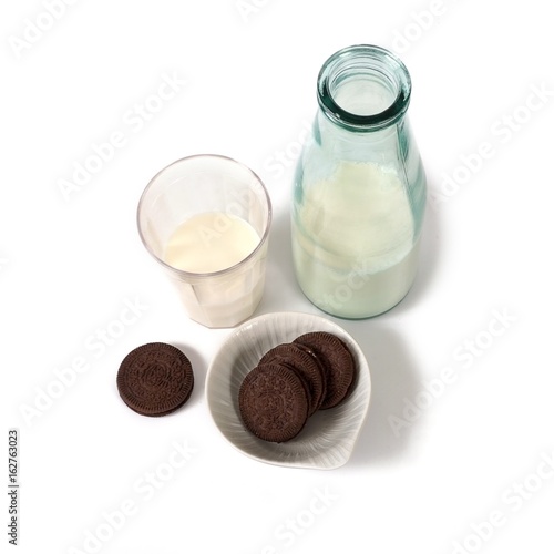 A bottle of milk, a glass of milk and chocolate chip cookies with a white stuffing