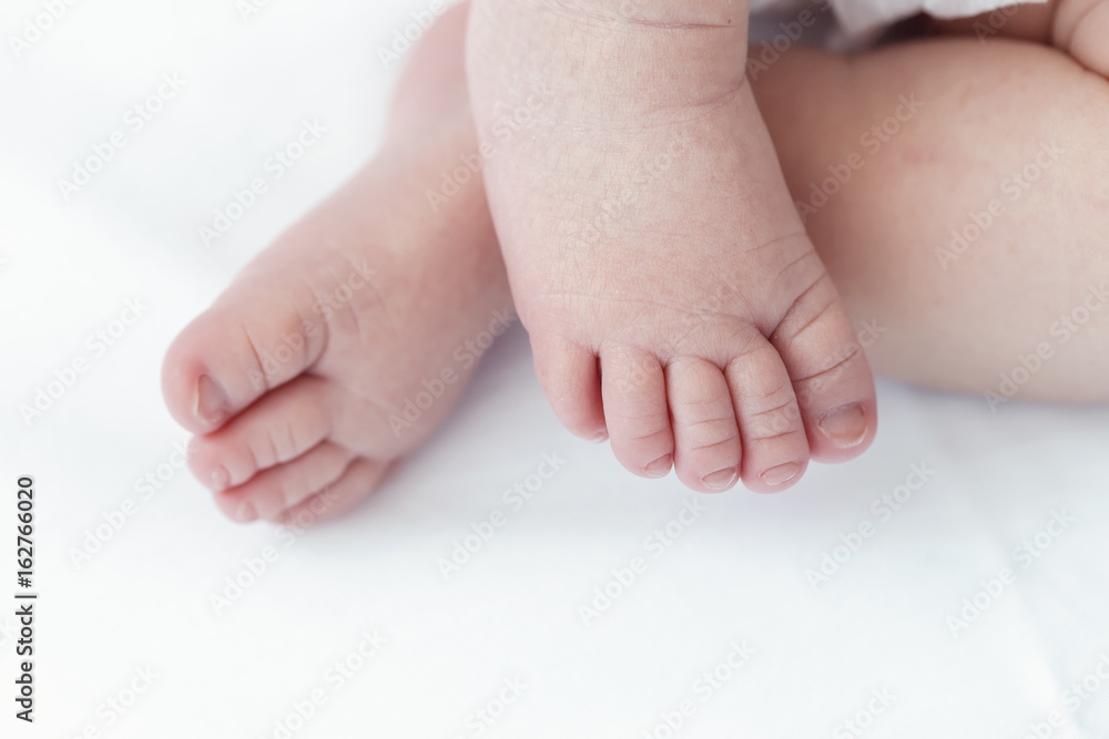 Close up of tiny adorable bare pink baby feet as the infant sleeps on white blanket Close up of tiny adorable bare pink baby feet as the infant sleeps on white blanket
