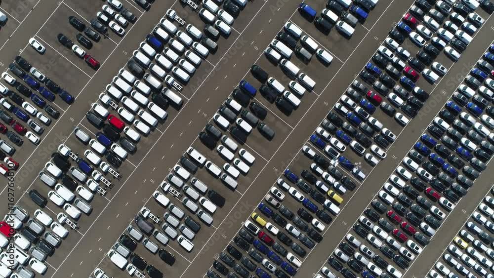 Aerial top down view above car lot with ready for transportation towards car dealers automobiles are white blue black and red colored and parked very close to each other industrial scenery 4k quality Aerial top down view above car lot with ready for transportation towards car dealers automobiles are white blue black and red colored and parked very close to each other industrial scenery 4k quality