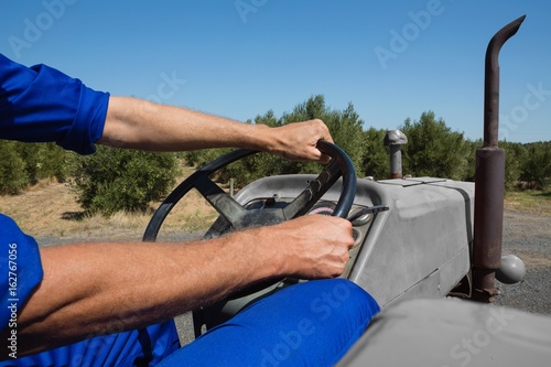 Mid-section of worker driving a tractor