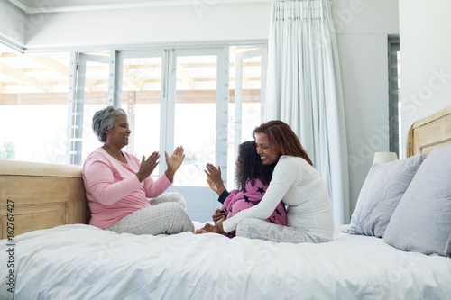 Family playing clapping games on bed in bedroom