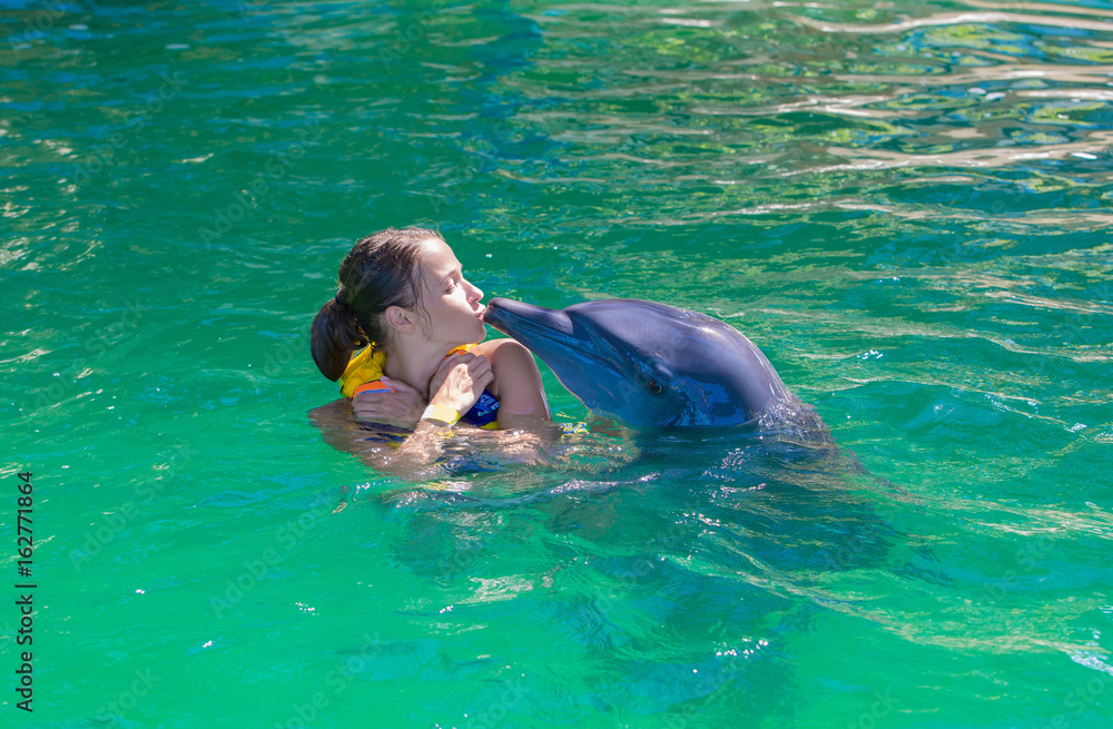 A girl, a model swims with dolphins. Man, a mammal, a dolphin.