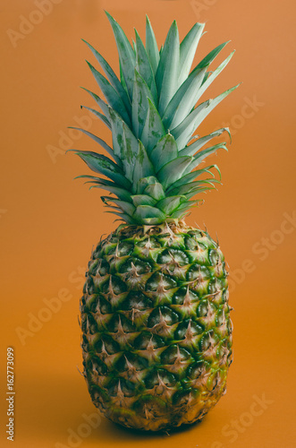 whole ripe pineapple on orange background  isolated