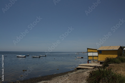Boote im Wasser mit einer kleinen Holzhütte am Strand © 36Grad Design