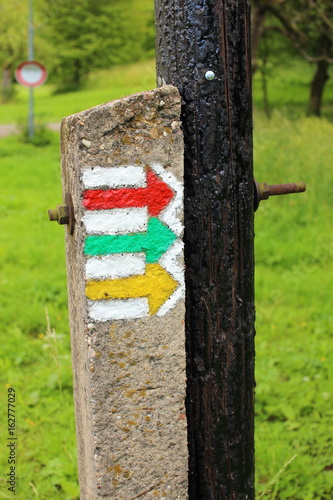 Tourist sign colorful arrows on the old wooden pole grounding