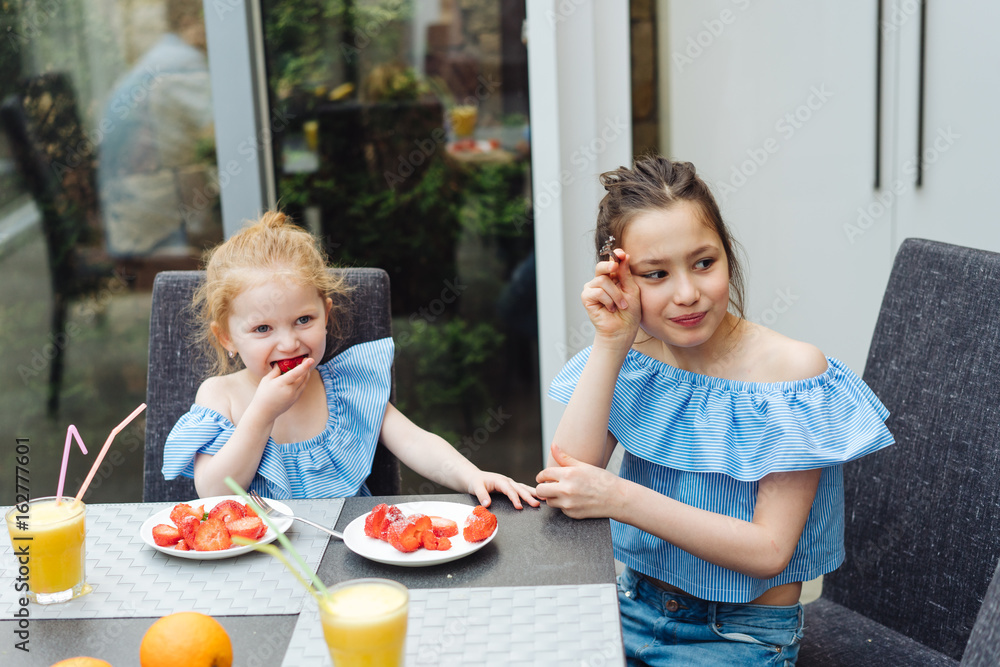 Two sisters drink juice in the kitchen Two sisters drink juice in the kitchen