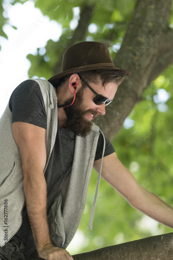 Handsome hipster guy with a fabric hat and sunglasses listening to music with earphones Handsome hipster guy with a fabric hat and sunglasses listening to music with earphones