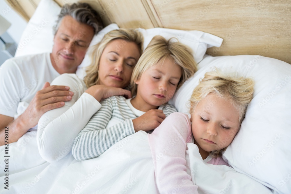 Family sleeping on bed in the bed room Family sleeping on bed in the bed room