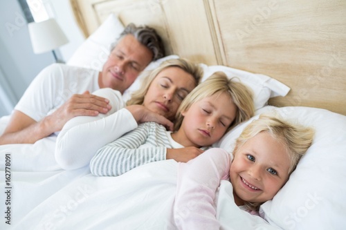 Family sleeping on bed in the bed room © WavebreakMediaMicro