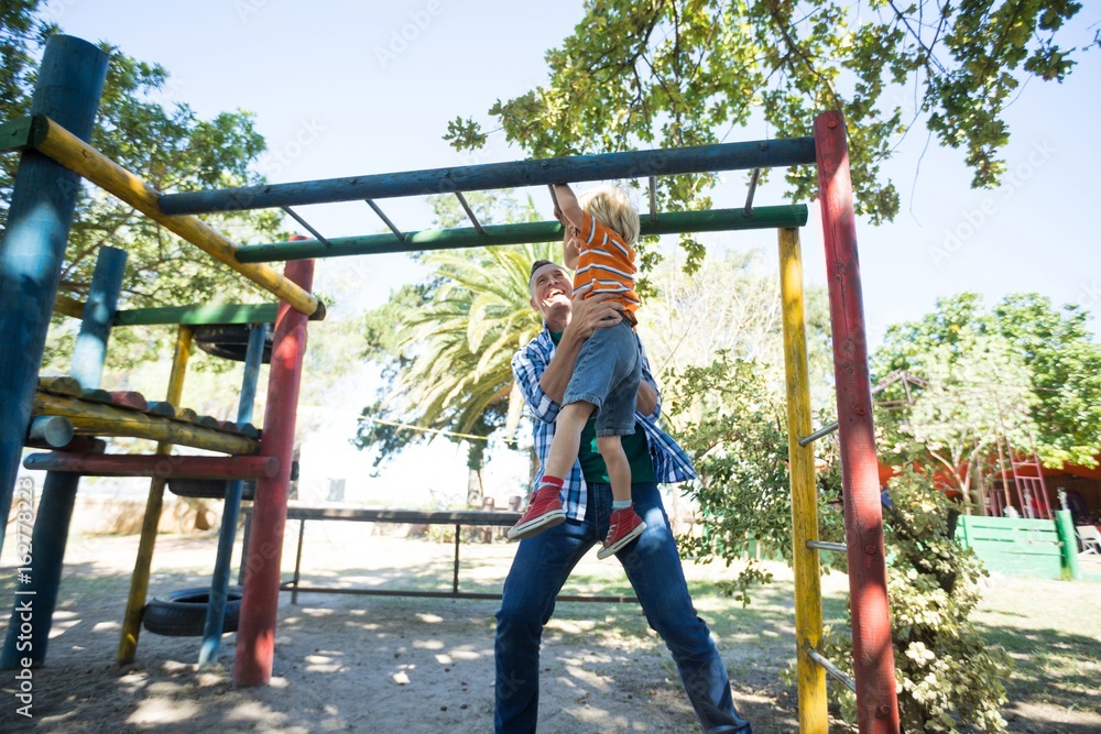 Low angle view of father assisting son in hanging on jungle gym Low angle view of father assisting son in hanging on jungle gym