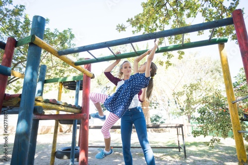 Happy mother looking at daughter hanging on jungle gym photo