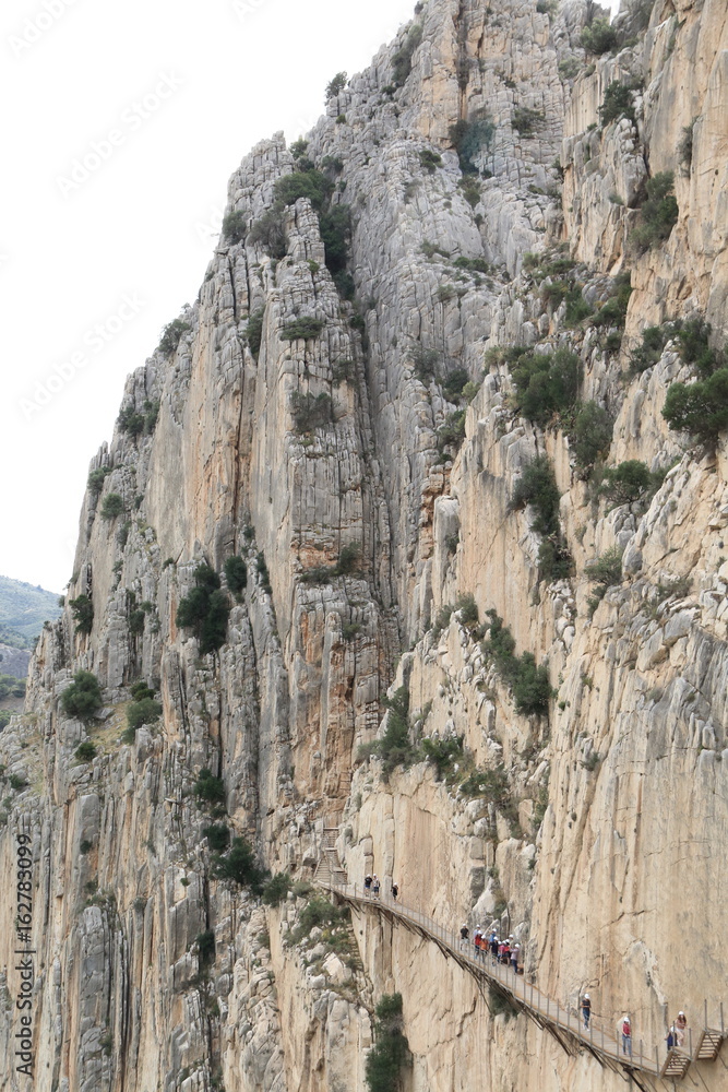 Hikers walking along the wooden walkways of the gorge of Los Gaitanes, in the Caminito del Rey, Malaga, Spain