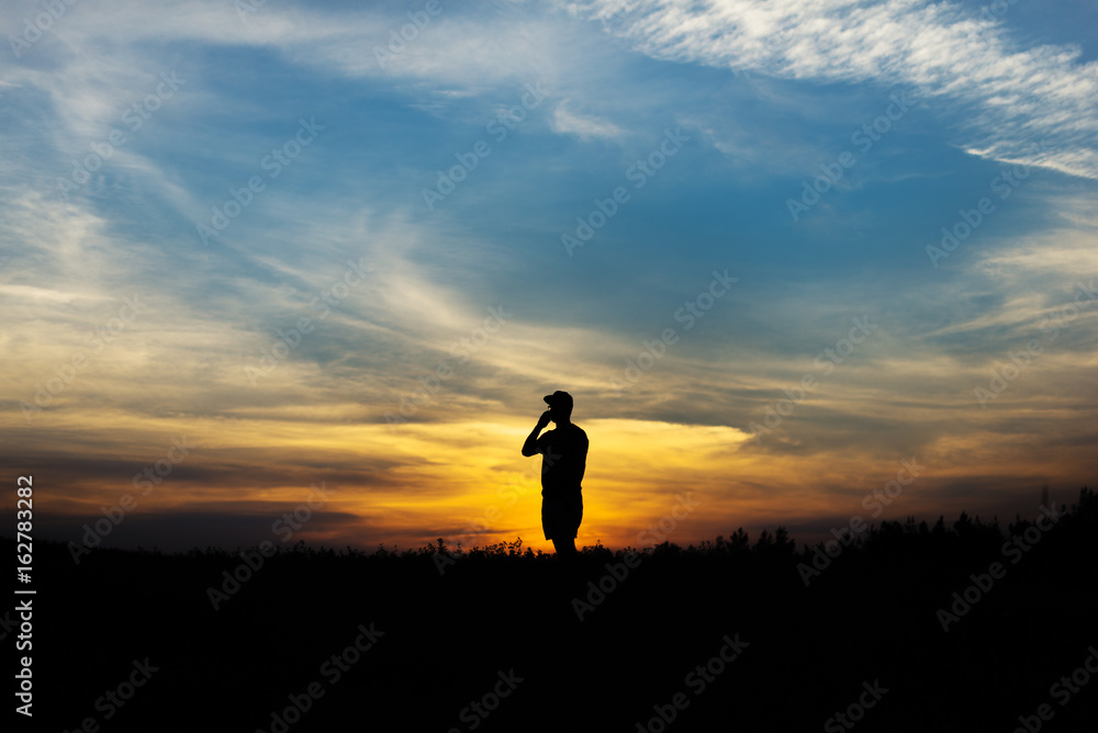 Silhouette of the person talking on the phone at sunset.
