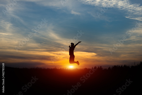 Silhouette of a cheerful man at sunset. Leap at sunset.