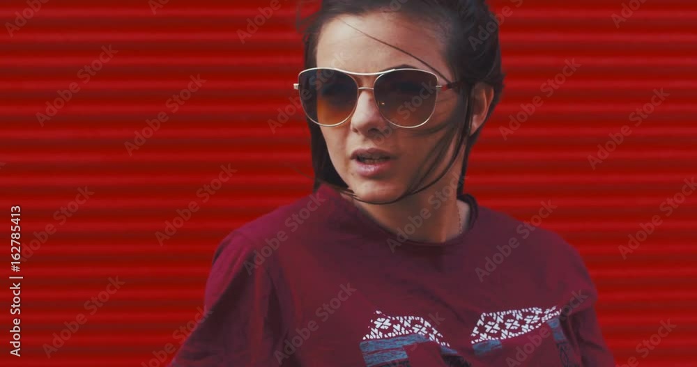 CU portrait of young teen girl against red metal wall, outdoors urban background. 4K UHD CU portrait of young teen girl against red metal wall, outdoors urban background. 4K UHD