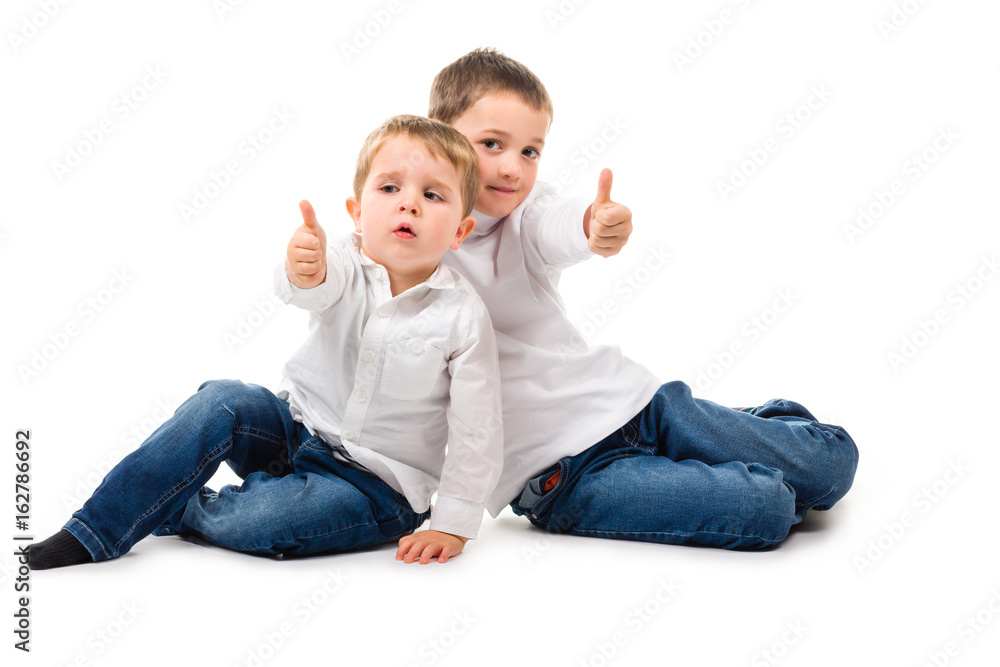 Little boys sitting on the floor giving thumbs up. Isolated on white Little boys sitting on the floor giving thumbs up. Isolated on white