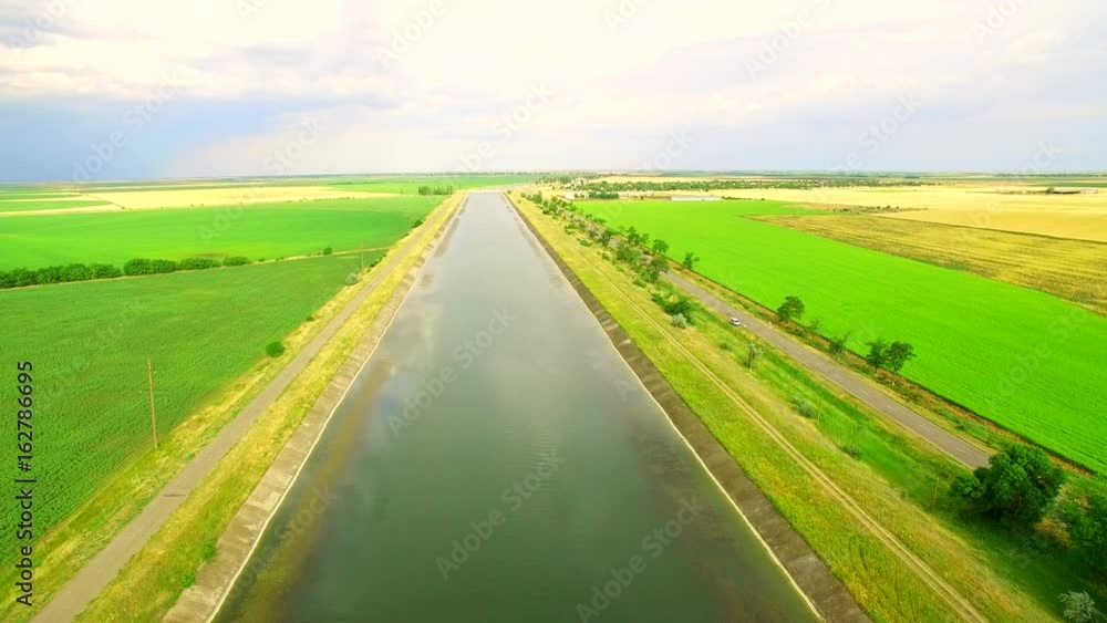 Water channel between the fields of green and yellow wheat for incorporation Water channel between the fields of green and yellow wheat for incorporation