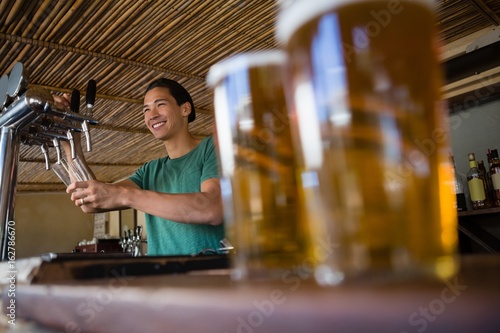 Close-up of beer glasses with bartender looking away