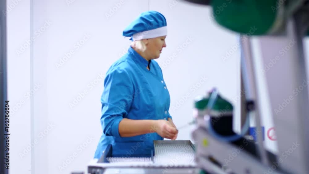 Pharmaceutical production equipment. Female worker working on pharmaceutical packaging line. Pharmacy production industry. Pharmaceutical vials production line. Vial medical production factory Pharmaceutical production equipment. Female worker working on pharmaceutical packaging line. Pharmacy production industry. Pharmaceutical vials production line. Vial medical production factory