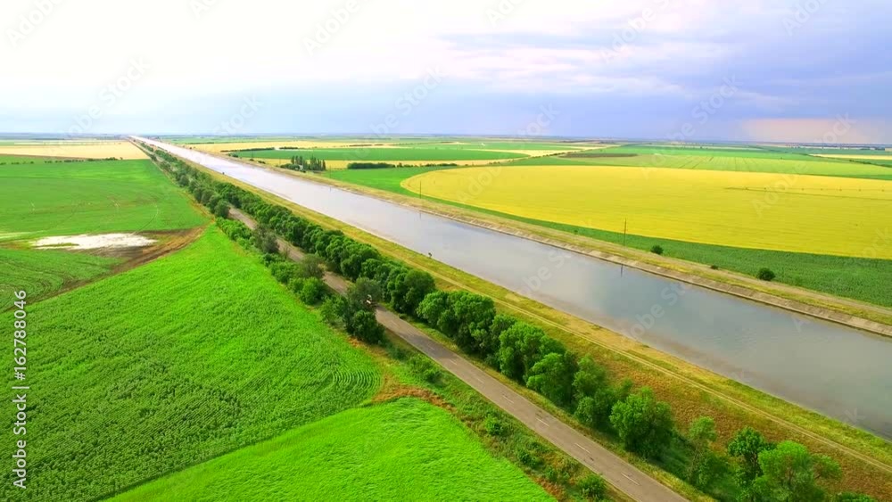 Water channel between the fields of green and yellow wheat for incorporation Water channel between the fields of green and yellow wheat for incorporation