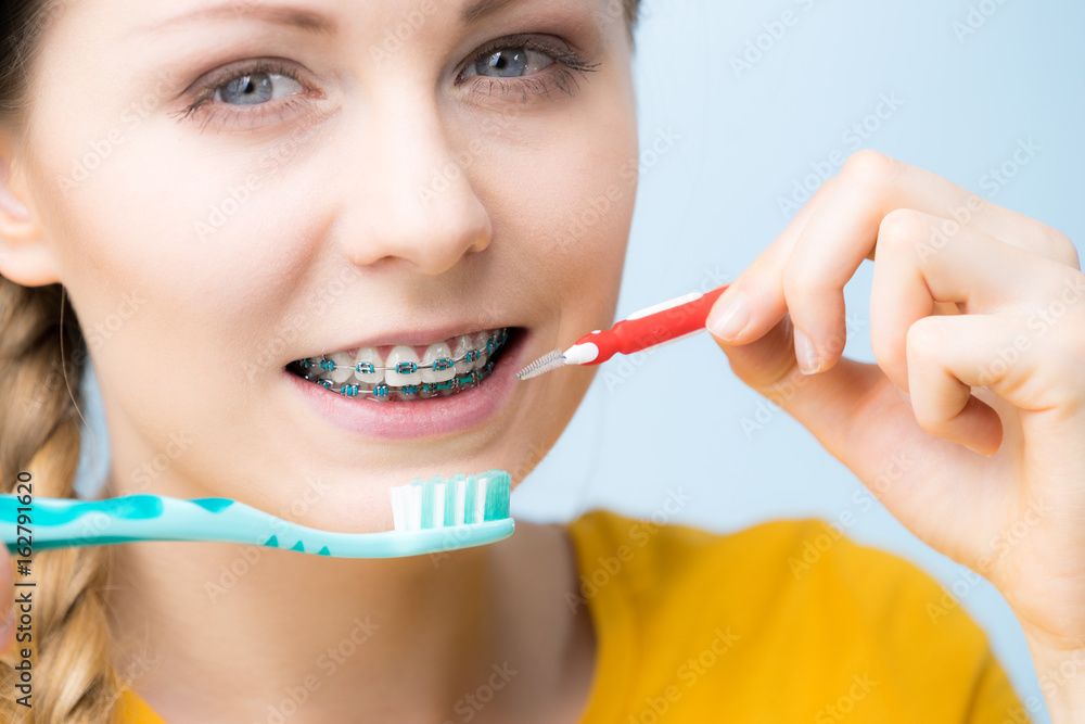 Woman smiling cleaning teeth with braces Woman smiling cleaning teeth with braces