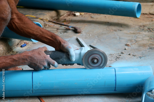 Asian workers use electric circular saw cutting the PVC pipe 