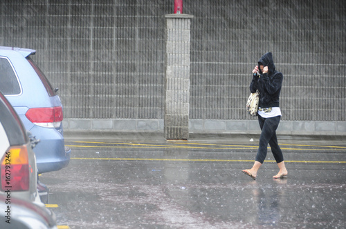 woman leaving store in a parking lot, walking in the rain
