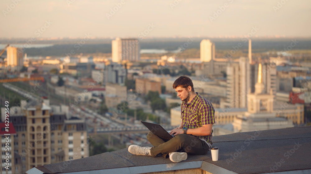 Hipster with laptop on roof