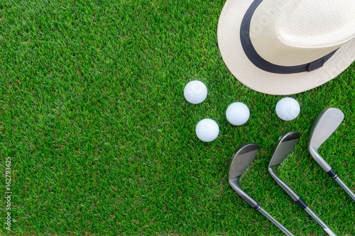 Golf concept : Panama hat, golf balls, golf iron clubs flat lay on green glass, with copy space.