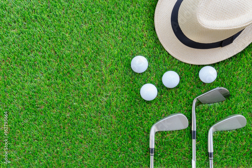 Golf concept : Panama hat, golf balls, golf iron clubs flat lay on green glass, with copy space.