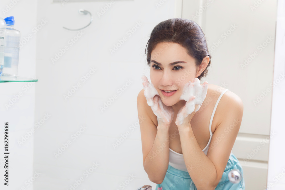 Woman happy cleanses the skin with foam in bathroom. Woman happy cleanses the skin with foam in bathroom.
