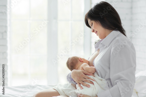 Fotótapéta Mother breastfeeding newborn in the bed