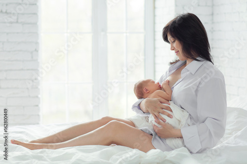 Mother breastfeeding newborn in the bed