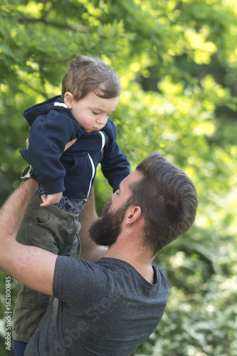 Young bearded hipster father holding his little son in park © cineberg