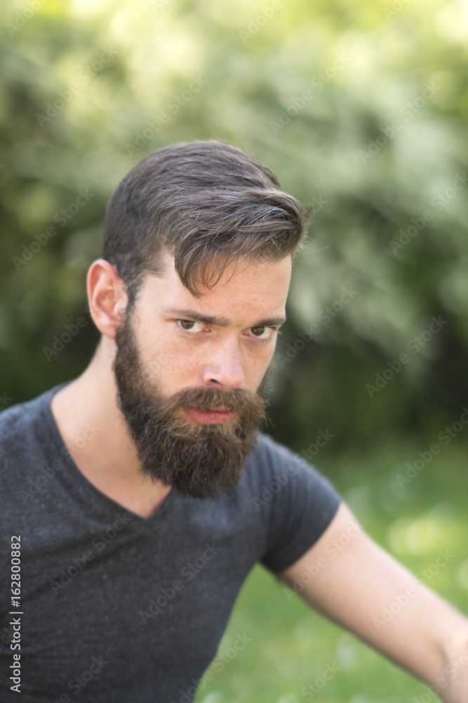 Frowned young bearded man in park Frowned young bearded man in park