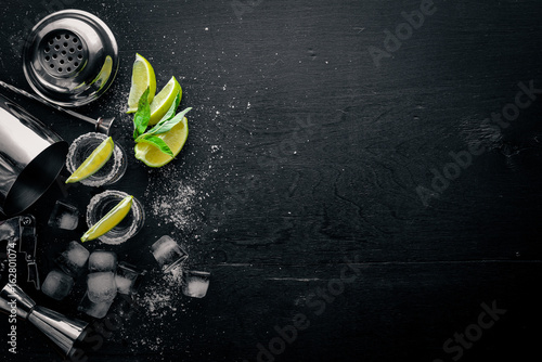 Tequila with lime and ice, on a black wooden surface. Top view. Free space.