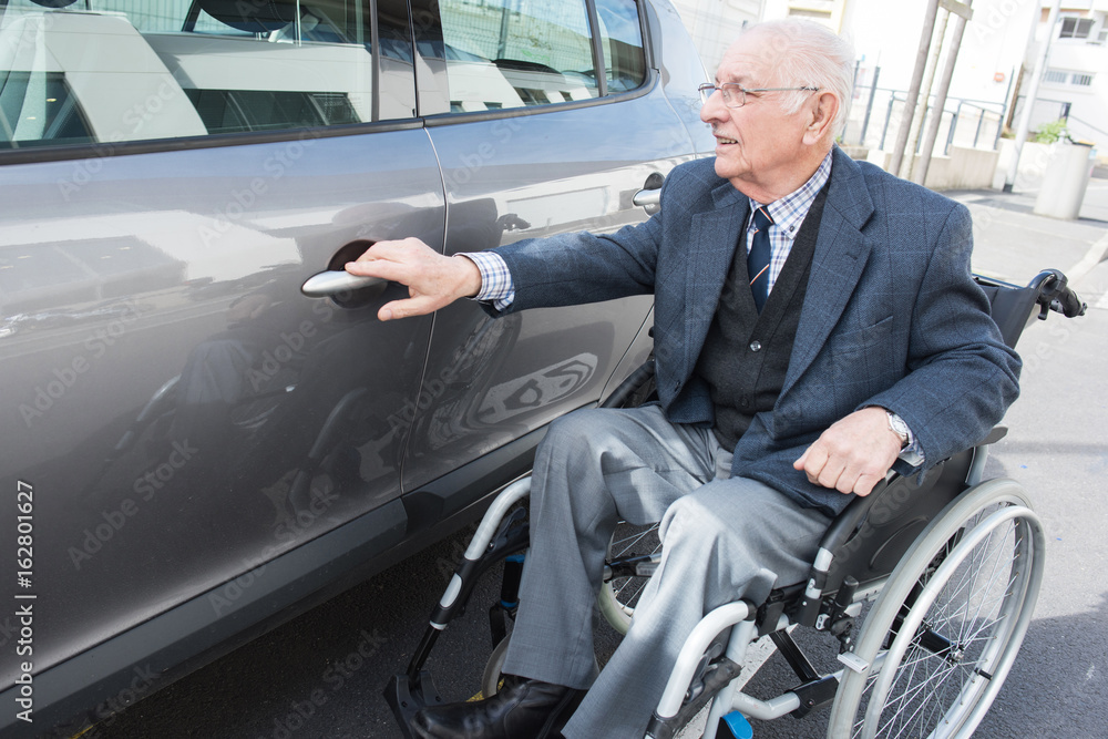 old man in a wheelchair next to his car old man in a wheelchair next to his car