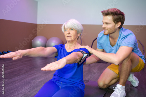 fitness instructor helping senior woman with posture