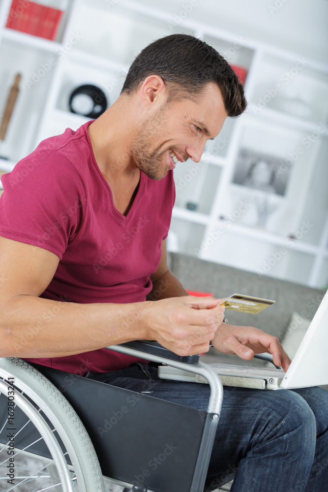 disabled man in wheelchair using credit card on the internet disabled man in wheelchair using credit card on the internet