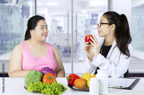 Asian doctor shows healthy foods for her patient